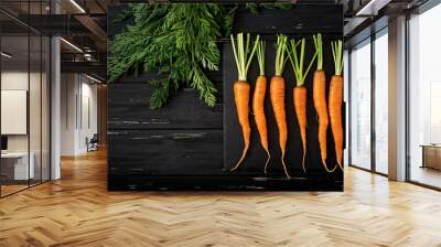 Bunch of fresh carrots with green leaves on  dark  wooden background. Flat lay. Top view Wall mural