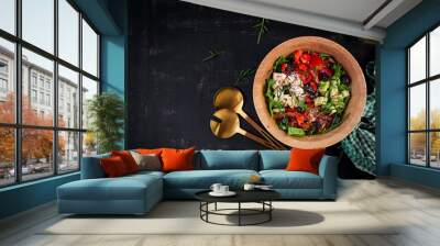 Fresh salad with avocado, tomatoes, mozzarella cheese, sweet peppers and black olives on wooden bowl. Top view, above Wall mural