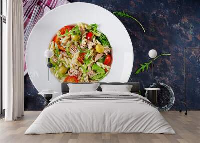 Pasta salad with tuna, tomatoes, olives, cucumber, sweet pepper and arugula on rustic background . Top view Wall mural