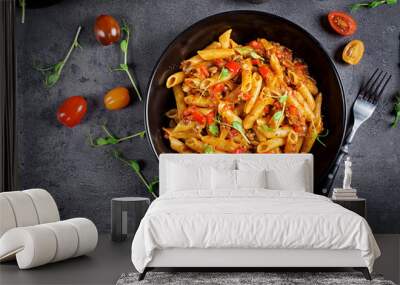 Penne pasta in tomato sauce with meat, tomatoes decorated with pea sprouts on a dark table. Top view Wall mural