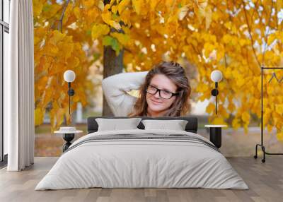 Beautiful young woman with yellow autumn wreath on bright backgr Wall mural