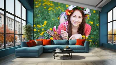 happy woman with wreath lying on a meadow with a bouquet of flowers Wall mural