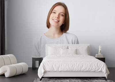 beautiful woman expresses happy emotions, has broad pleasant smile, wears white longsleeve and feels satisfied. Isolated over white background Wall mural