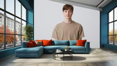 portrait of handsome attractive young man with short haircut and blue eyes wears beige t shirt stand Wall mural