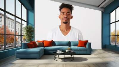 Portrait of serious confident african american young man with curly hair wears t shirt looks pensive and thinking isolated over white background Wall mural