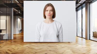 Portrait of serious unhappy young woman in longsleeve standing and frowning her face isolated over white background Looking directly in camera Wall mural