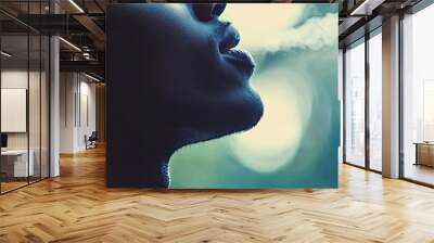 A close-up of a person exhaling smoke, creating an artistic atmosphere with a blurred background and soft light effects. Wall mural