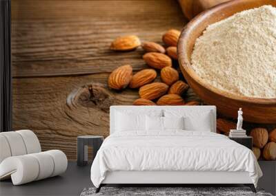 Almond flour in a bowl surrounded by almonds on a wooden table. Wall mural