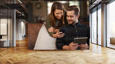 Get this app on your tablet. Cropped shot of a young couple using a cellphone and a digital tablet at home. Wall mural