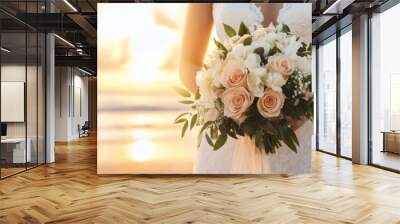 A bride holding a beautiful bouquet of roses and orchids at sunset, symbolizing love and celebration on her special day. Wall mural