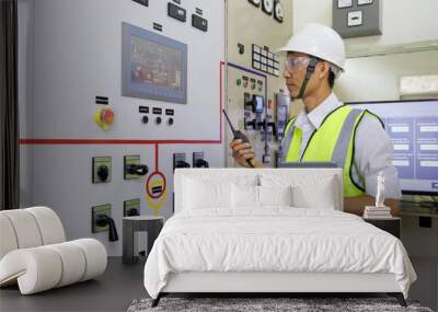 Experienced electrician working in power plant control room. Engineer working on the checking status switchgear electrical energy distribution substation. Wall mural