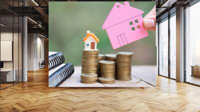 Human hand putting house model on coins stack,  planning savings money of coins to buy a home concept, mortgage and real estate investment.  saving or investment for a house. Wall mural