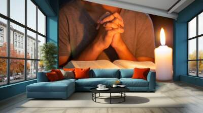 Religious concepts, The young man prayed on the Bible in the room and lit the candles to illuminate. Wall mural