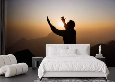 Silhouette of a man is praying to God on the mountain. Praying hands with faith in religion and belief in God on blessing background. Power of hope or love and devotion. Wall mural