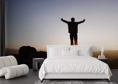 Silhouette of  man rise hand up on top of mountain and sunset sky abstract background. Freedom and travel adventure concept. pray or Praying, remembering God, Copy space . Wall mural