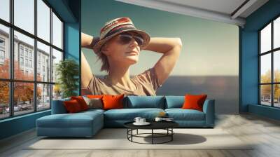 Concept of freedom, happiness, tourism, adventure and leisure. Attractive middle-aged woman in hat, keep your hands to your head and enjoy picturesque landscape at resort in sunny light Wall mural