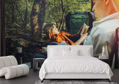 Two young girls relax on camping and read books Wall mural