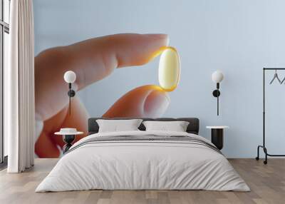 A hand holding a single, transparent, yellow capsule.  The capsule is illuminated from behind, creating a soft glow.  The background is a simple, muted gray. Wall mural