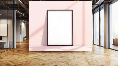 A minimalist black-framed empty picture frame casts shadows on a soft pink wall, creating a serene and clean aesthetic. Wall mural