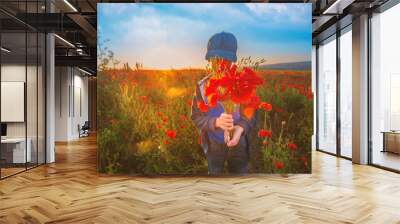 A boy and a bouquet of poppies in a field on a summer day Wall mural