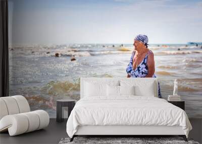 An old woman in a bathing suit with a cane went into the sea knee-deep Wall mural