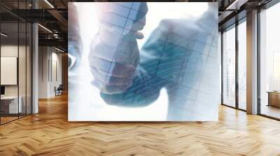 Business, finance and investment background. Business teamwork, double exposure of businessman making a handshake and corporate business team working on digital tablet at office Wall mural