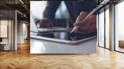 Business man using stylus pen on digital tablet and working on laptop in modern office Wall mural