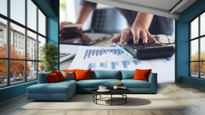 Business man working at office with digital tablet and laptop computer, using calculator to calculate financial report graph data documents on desk, close up. Business plan strategy and technology Wall mural