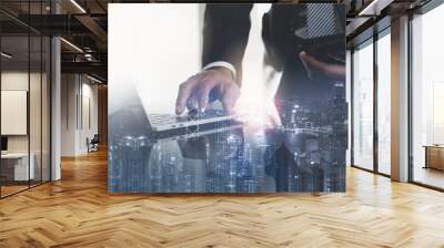 Business technology, finance and investment concept. Double exposure of businessman working on laptop computer in modern office and city scape Wall mural