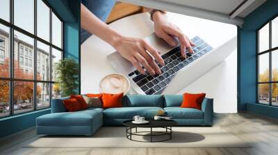 Casual business woman hand typing on laptop computer on table, online working, surfing the internet. Female freelancer working in coffee shop or home office, close up, freelance lifestyle concept Wall mural