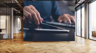 casual man working on digital tablet and laptop computer at home office Wall mural