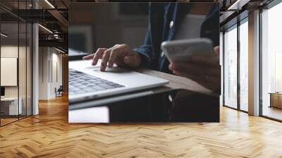 Closeup of business woman using mobile smart phone and working on laptop computer with digital tablet on office table at home Wall mural