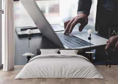 Closeup of businessman working on laptop computer with digital tablet and mobile phone on office table. Business man manager searching the information, surfing the internet on laptop Wall mural