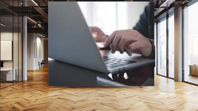 Man hands typing on laptop computer keyboard and surfing the internet on office table, online working, business and technology, internet network communication concept, close up Wall mural