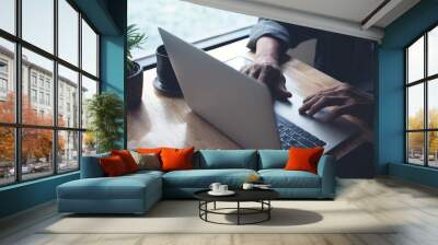 Man working at home, typing and searching data on laptop computer on office table. Freelancer at work. Casual business, online job, telecommuting concept Wall mural