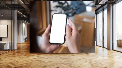 Mockup, woman's hand holding using mobile phone at coffee shop with copy space, white blank screen for text, mobile app design and advertising, online marketing Wall mural