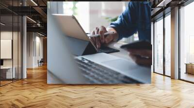 Multitasking business man busy working on laptop computer, digital tablet and using mobile smartphone from home office Wall mural