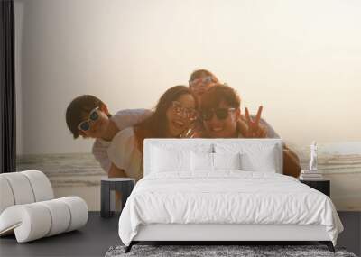 Asian young happy family enjoy vacation on beach in the evening. Dad, mom and kid set camera for take photo while relax together near sea when sunset. Lifestyle travel holiday vacation summer concept. Wall mural