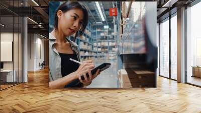 Attractive young Asia businesswoman manager looking for goods using digital tablet checking inventory levels standing in retail shopping center. Distribution, Logistics, Packages ready for shipment. Wall mural