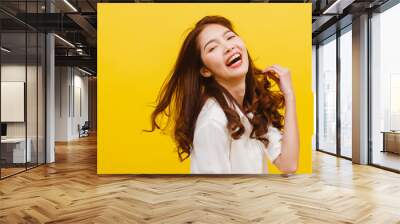 Happy excited young funny Asian lady listening to music and dancing in casual clothing over yellow background. Human emotions, facial expression, studio portrait, lifestyle concept. Wall mural