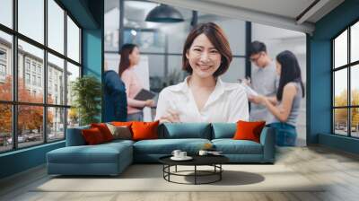 Portrait of successful beautiful executive businesswoman smart casual wear looking at camera and smile, arms crossed in modern office workplace. Young Asia lady standing in contemporary meeting room. Wall mural