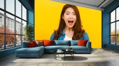 Portrait of young Asian lady with positive expression, joyful surprise funky, dressed in casual clothing and looking at the camera over yellow background. Happy adorable glad woman rejoices success. Wall mural