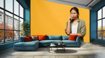 Young Asia lady talk by phone with negative expression, excited screaming, cry emotional angry in casual cloth and stand isolated on yellow background with blank copy space. Facial expression concept. Wall mural