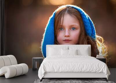 Portrait of a beautiful little girl with blue eyes on a brown background Wall mural