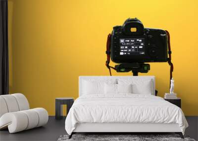 A back black camera on tripod shooting to yellow screen. Wall mural