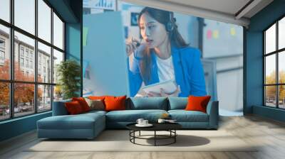 Businesswoman works late in her office, focused on her job surrounded by technology, taking notes and communicating Wall mural