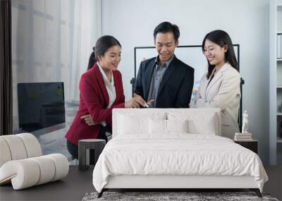 Group of young business people discussing business while working by using line chart  and laptop in the office together  Wall mural