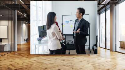 Group of young business people discussing business while working by using line chart  and laptop in the office together  Wall mural