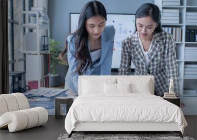 Two businesswomen collaborating in an office, analyzing financial documents and strategizing for success. Focused on teamwork, problem-solving, and effective communication Wall mural