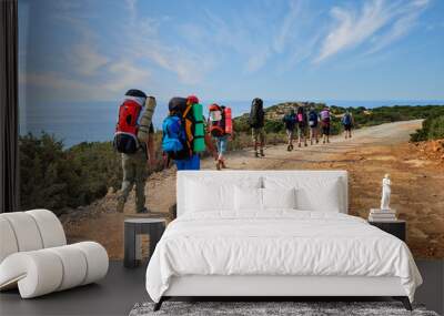 group of tourists with large backpacks are on road sea Wall mural